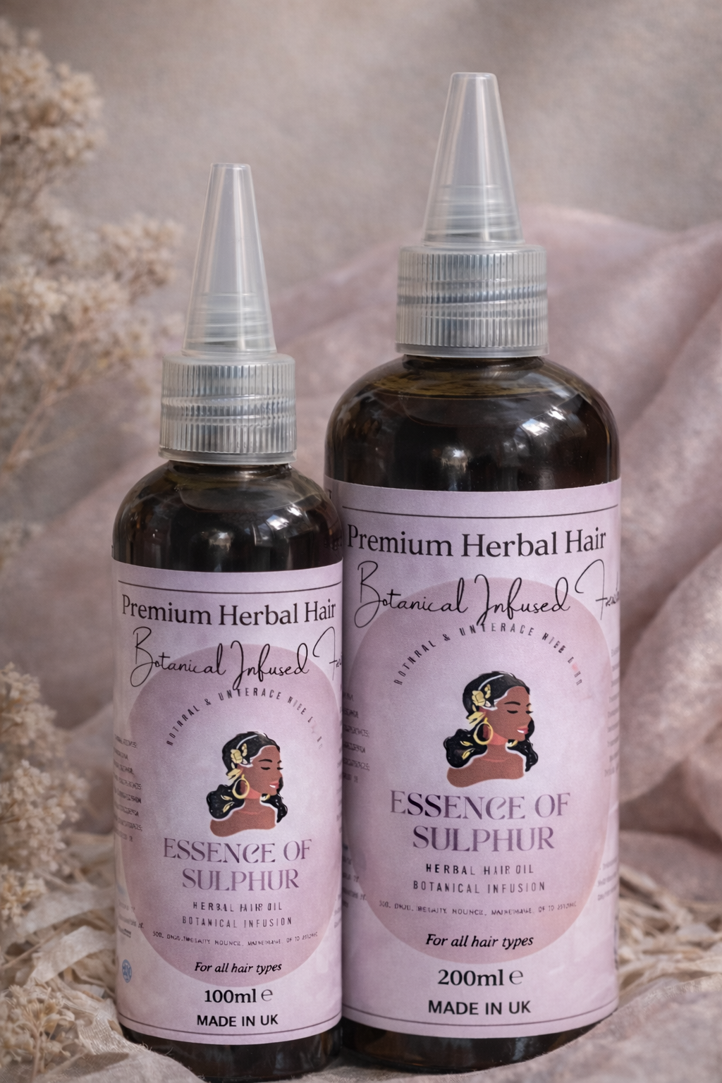 Two bottles of 'Essence of Sulphur' , 100ml and 200ml herbal hair oil with labels on a neutral background.